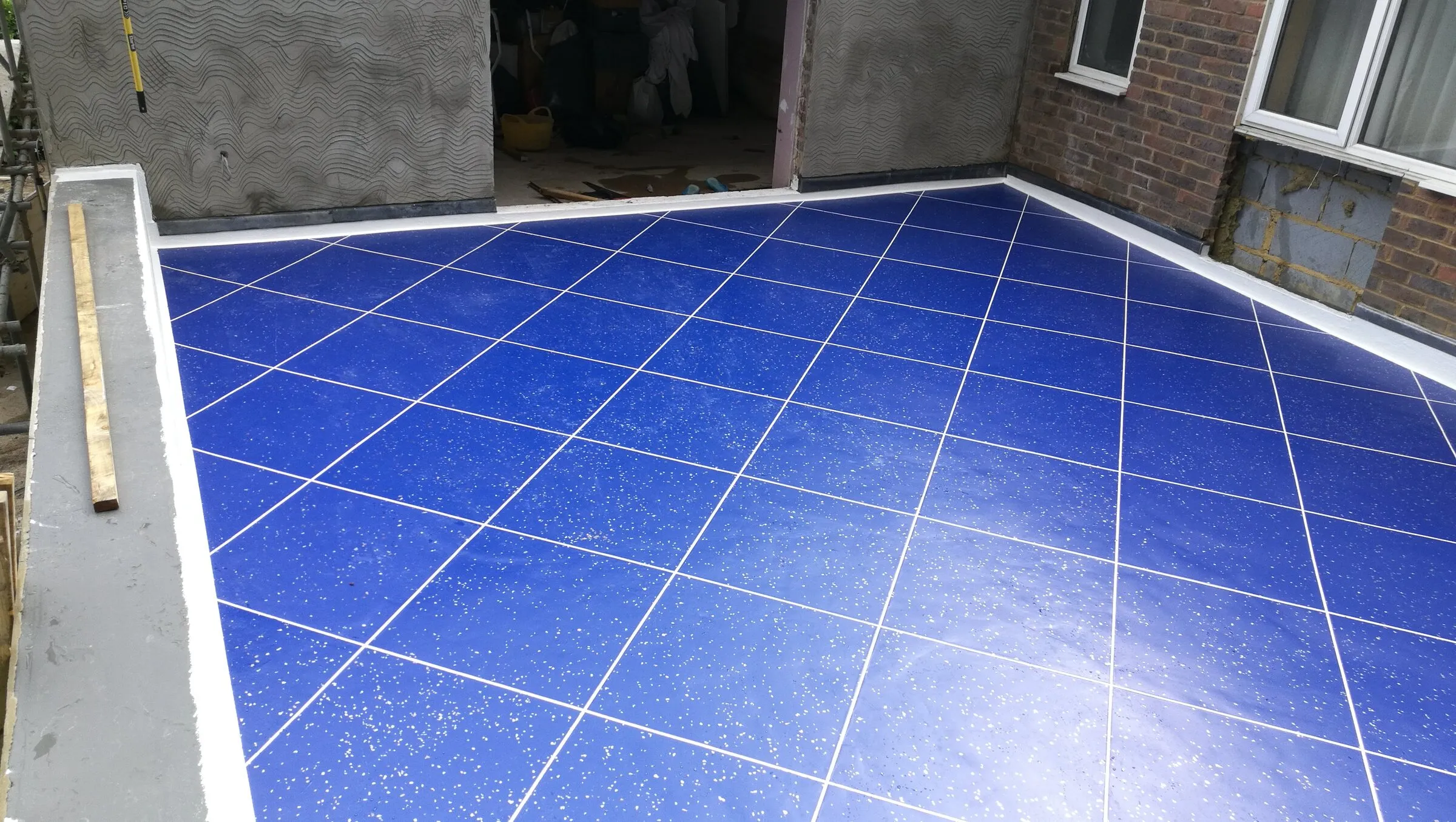Blue tile-effect balcony with a rendered upstand and open doorway