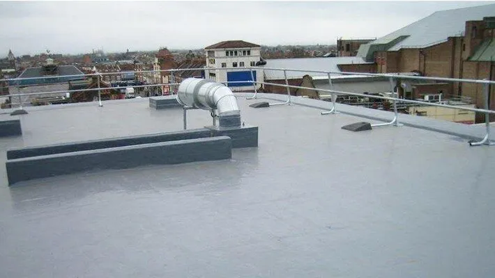 Light grey single ply commercial roof with ductwork, handrails and town views