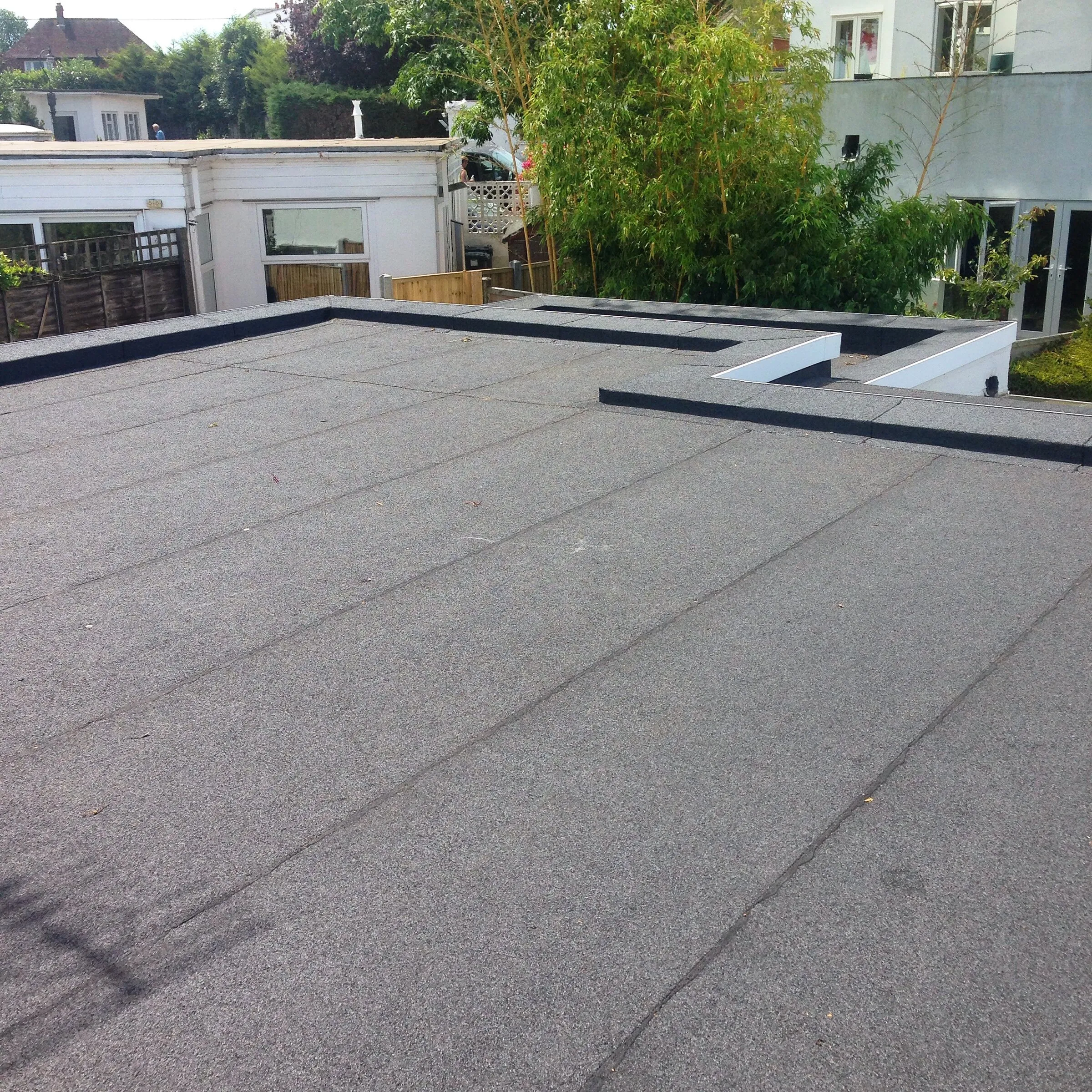 Dark waterproofed flat roof on a single-storey extension with crisp upstands and trims