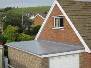 Light grey flat roof on a brick garage beside the gable of the house