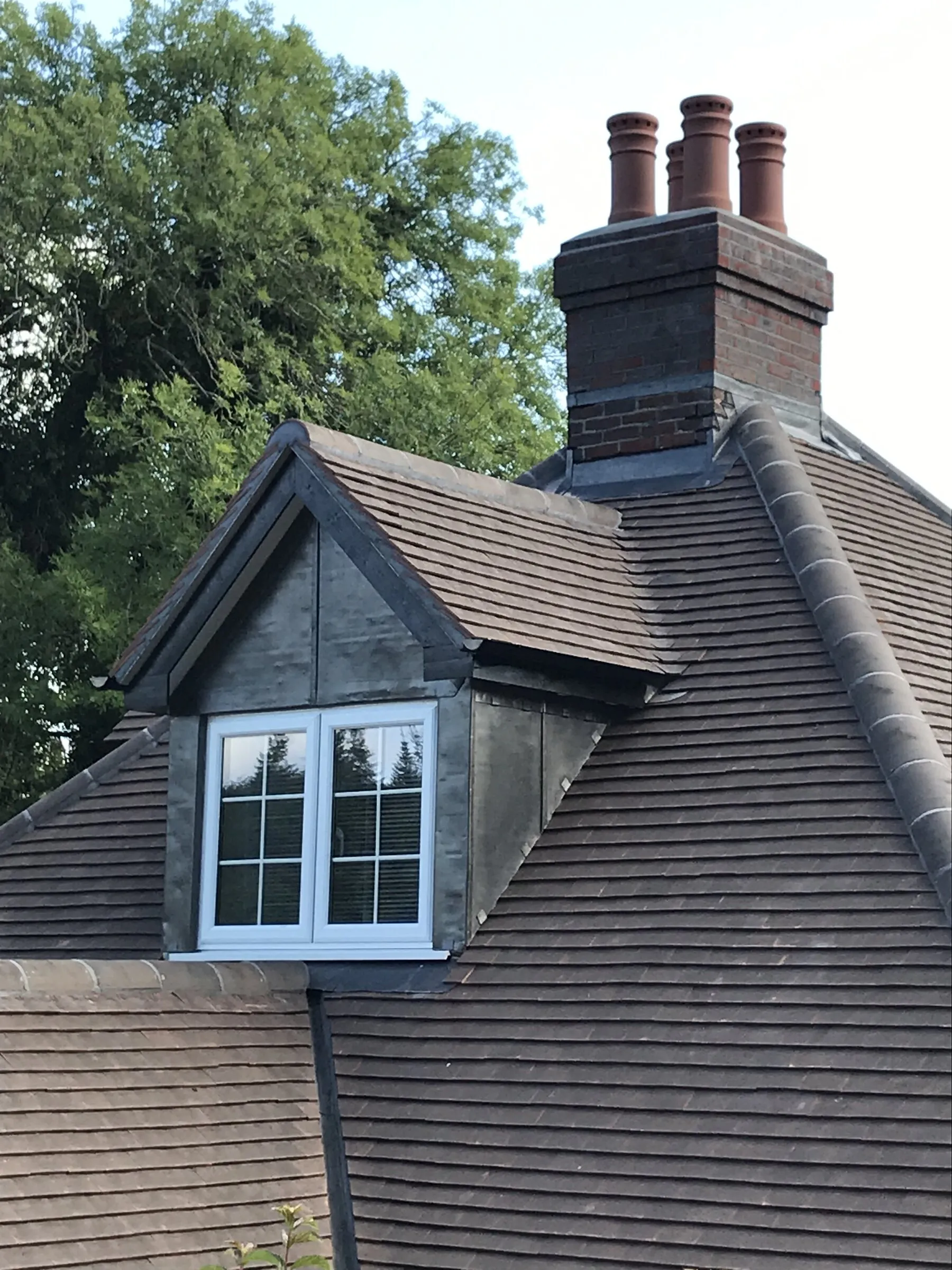 Tiled roof with a lead-clad dormer window and a tall brick chimney