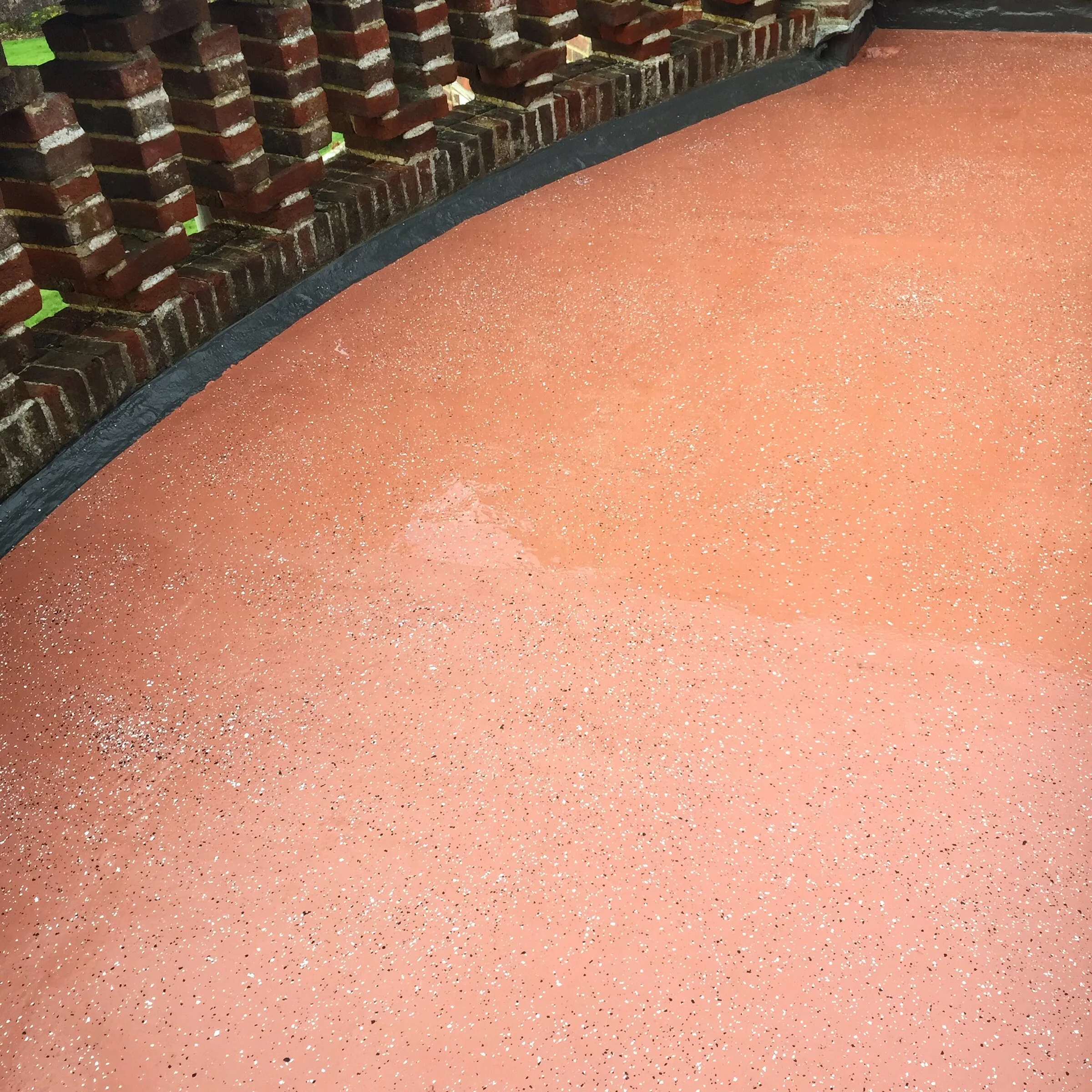 Red liquid resin terrace finished up to a brick balustrade with decorative openings