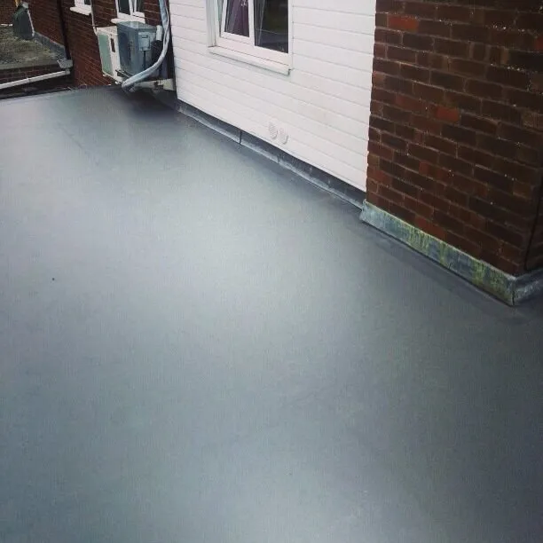 Grey single ply membrane running up to white cladding and a brick wall on a small flat roof