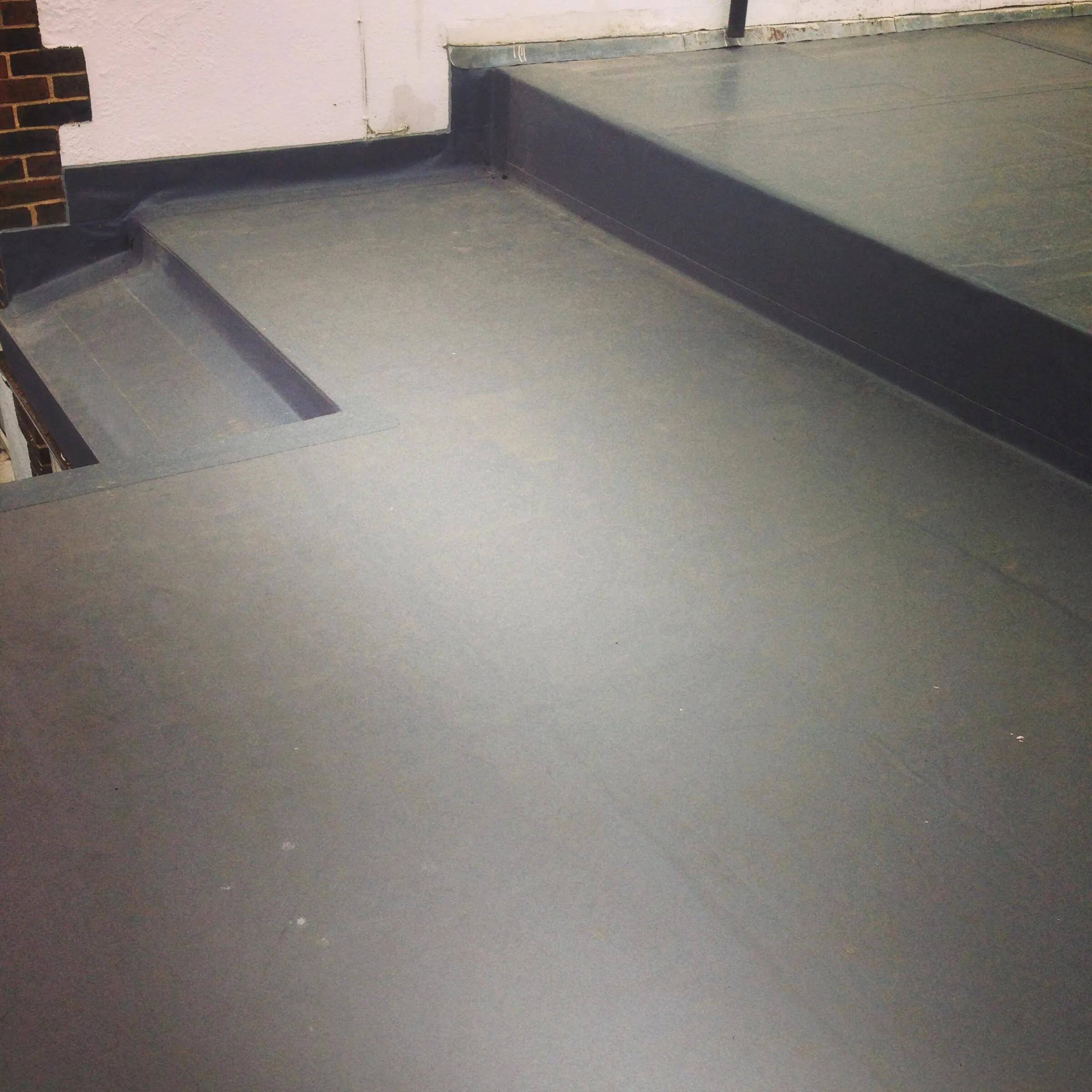 Grey single ply membrane on a flat roof, stepping down over a welded upstand detail