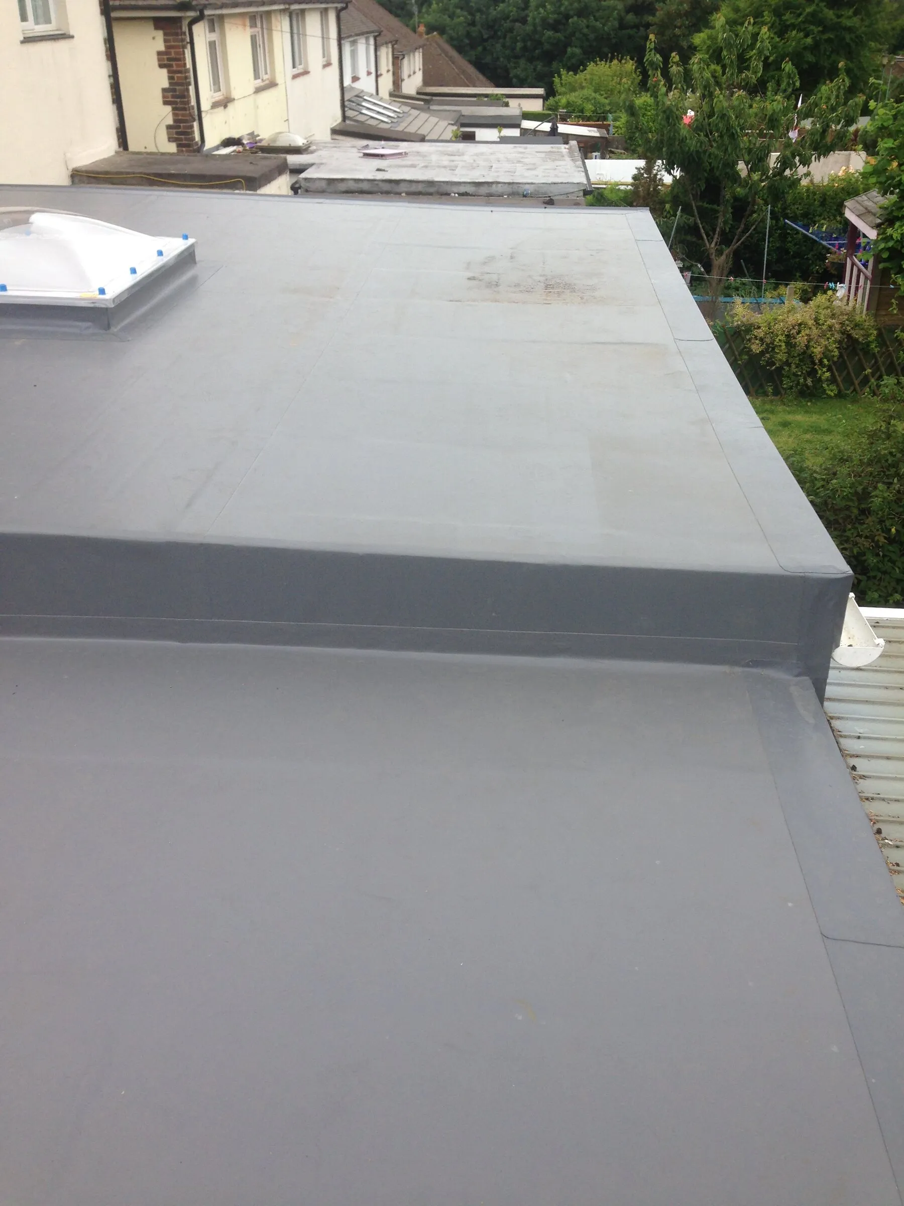 Grey single ply flat roof with a dome rooflight and neat upstand