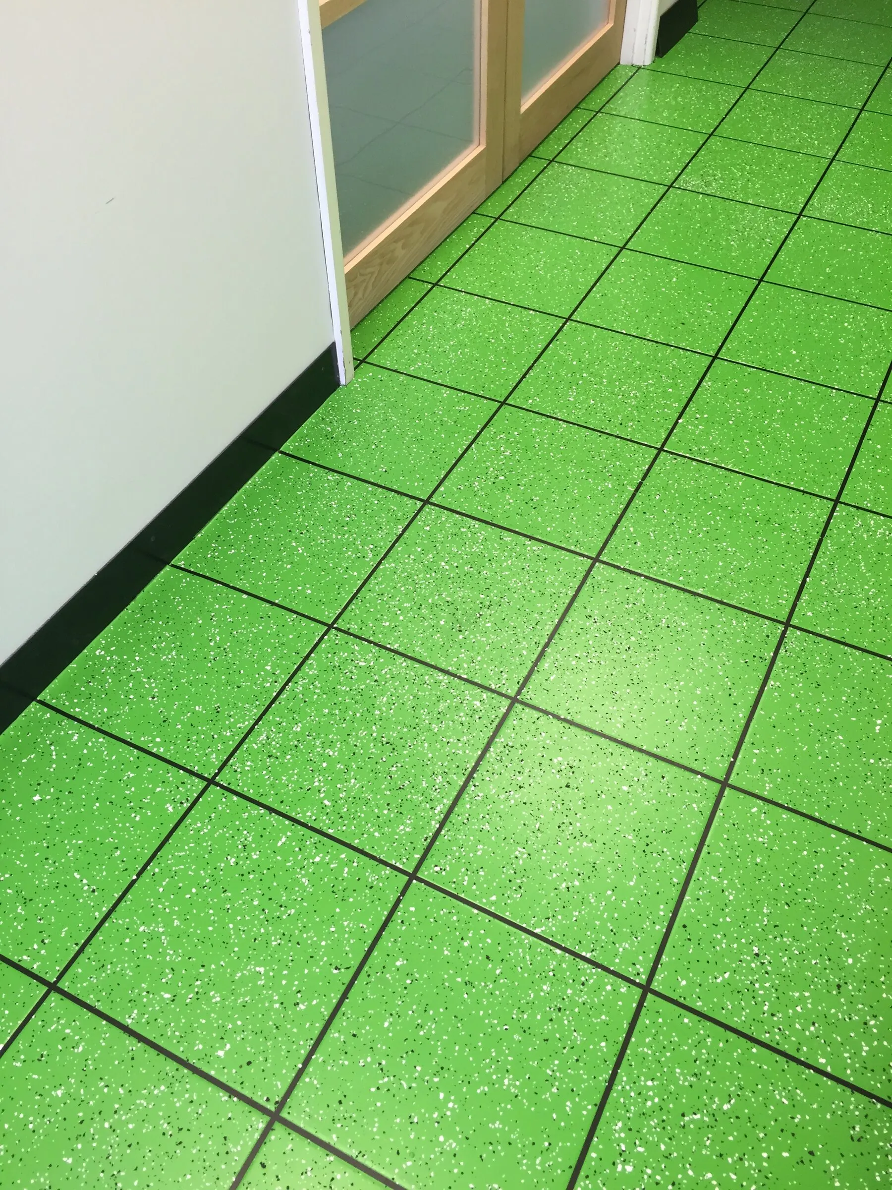Green speckled tile-effect resin walkway along an interior corridor