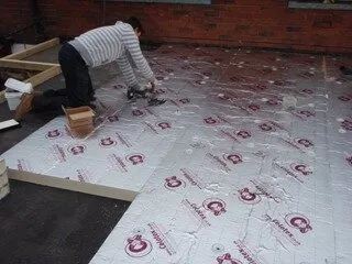 Roofer laying rigid insulation boards across a flat roof deck